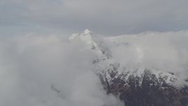 4K aerial stock footage flying by snow covered peak, low clouds, Chugach Mountains, Alaska Aerial Stock Footage | AK0001_0559