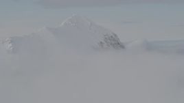 4K aerial stock footage flying by snow covered peak, surrounded by clouds, Chugach Mountains, Alaska Aerial Stock Footage | AK0001_0562