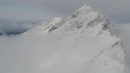 4K aerial stock footage flying over low clouds, approaching a snowy peak, Chugach Mountains, Alaska Aerial Stock Footage | AK0001_0563