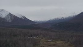4K aerial stock footage flying by wooded valley, houses, snow-capped Chugach Mountains, Alaska Aerial Stock Footage | AK0001_0624