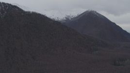4K aerial stock footage flying by wooded hills, snow-capped mountain peaks, Chugach Mountains, Alaska Aerial Stock Footage | AK0001_0625