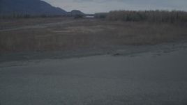 4K aerial stock footage fly over river banks, grassland, approach bend, during winter, Knik River, Alaska Aerial Stock Footage | AK0001_0698
