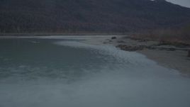 4K aerial stock footage flying low over river, approaching tree-lined shore, winter, Knik River, Alaska Aerial Stock Footage | AK0001_0704