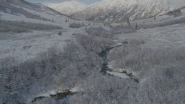 4K aerial stock footage flying low over river, frosty valley, snow-covered Chugach Mountains, Alaska Aerial Stock Footage | AK0001_0802