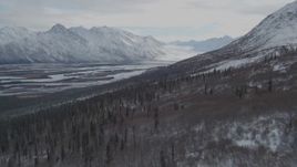 4K aerial stock footage flying down wooded hills toward the snowy Tazlina River Valley, Alaska Aerial Stock Footage | AK0001_0891
