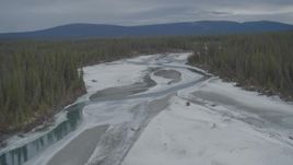 4K aerial stock footage fly over icy, snow covered river, ascend to show forest during winter, Tazlina River Valley, Alaska Aerial Stock Footage | AK0001_0902