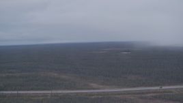 4K aerial stock footage flying by forest during a rain storm to reveal a highway in the Alaskan Wilderness Aerial Stock Footage | AK0001_1019