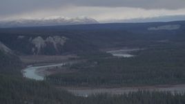 4K aerial stock footage the Tazlina River at bottom of forested gorge, snowy mountains in the background, Alaska Aerial Stock Footage | AK0001_1024