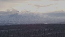 4K aerial stock footage snow and cloud capped Chugach Mountains near forest, Alaskan Wilderness Aerial Stock Footage | AK0001_1051