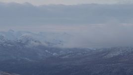 4K aerial stock footage low clouds eclipsing snowy Talkeetna Mountains, Alaska Aerial Stock Footage | AK0001_1058