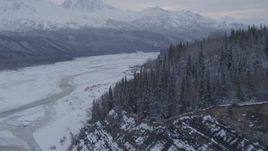 4K aerial stock footage flying over snow covered, tree lined cliffs following Matanuska River, Alaska Aerial Stock Footage | AK0001_1086