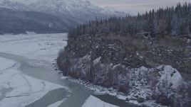 4K aerial stock footage following the Matanuska River toward snow covered, tree topped cliff, Alaska Aerial Stock Footage | AK0001_1087