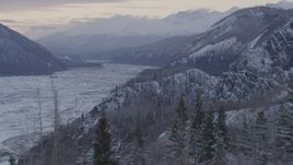 4K aerial stock footage flying over a snow covered, wooded cliff revealing Matanuska River Valley, Alaska Aerial Stock Footage | AK0001_1092