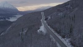 4K aerial stock footage follow Glenn Highway, snow covered, wooded hills, Sutton, Alaska, twilight Aerial Stock Footage | AK0001_1100
