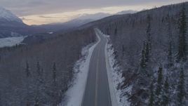 4K aerial stock footage following Glenn Highway and snow covered forest near Sutton at twilight, Alaska Aerial Stock Footage | AK0001_1101
