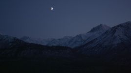4K aerial stock footage the moon over the snow covered Chugach Mountains at night, Alaska Aerial Stock Footage | AK0001_1108