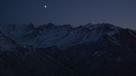 4K aerial stock footage the moon over the snow covered Chugach Mountains at night, Alaska Aerial Stock Footage | AK0001_1122
