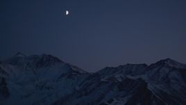 4K aerial stock footage the moon over the snow covered Chugach Mountains at night, Alaska Aerial Stock Footage | AK0001_1126
