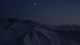 4K aerial stock footage the moon above the snow covered Chugach Mountains at night, Alaska Aerial Stock Footage | AK0001_1138