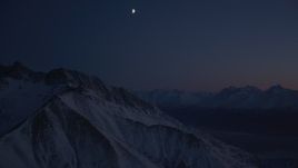 4K aerial stock footage the moon over snowy Chugach Mountains, tilt down to valley, Alaska, night Aerial Stock Footage | AK0001_1139