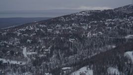 4K aerial stock footage flying over snow covered, wooded hills and homes in Eagle River, Alaska Aerial Stock Footage | AK0001_1164