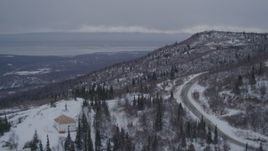 4K aerial stock footage flying over a home in snow covered wooded hills near Eagle River, Alaska Aerial Stock Footage | AK0001_1166