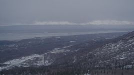 4K aerial stock footage over snowy, wooded slope, Chugach Mountains revealing Chugiak, Alaska Aerial Stock Footage | AK0001_1167