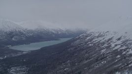 4K aerial stock footage flying over snowy summit revealing Eklutna Lake and Chugach Mountains, Alaska Aerial Stock Footage | AK0001_1182