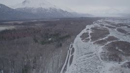 4K aerial stock footage flying along wooded, snow covered riverbank in Knik River Valley, Alaska Aerial Stock Footage | AK0001_1219
