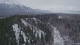 4K aerial stock footage following a river next to snow covered, wooded hills, Knik River Valley, Alaska Aerial Stock Footage | AK0001_1224