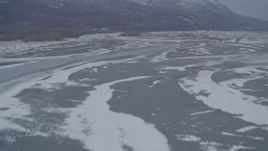 4K aerial stock footage flying over rivers toward snow covered wooded hills, Knik River Valley, Alaska Aerial Stock Footage | AK0001_1235