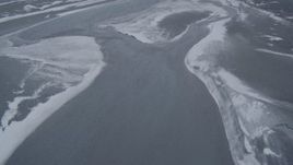 4K aerial stock footage following a river with snow blowing off the shore, Knik River Valley, Alaska Aerial Stock Footage | AK0001_1250
