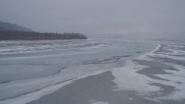 4K aerial stock footage following a river and snow near tree lined riverbank, Knik River Valley, Alaska Aerial Stock Footage | AK0001_1257