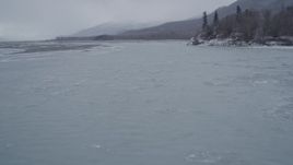 4K aerial stock footage following a river toward a snow covered, wooded bank, Knik River Valley, Alaska Aerial Stock Footage | AK0001_1268