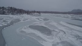 4K aerial stock footage following icy river toward snow covered, wooded hill, Knik River Valley, Alaska Aerial Stock Footage | AK0001_1270