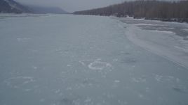 4K aerial stock footage following an icy river and tree lined, snowy riverbank, Butte, Alaska Aerial Stock Footage | AK0001_1272