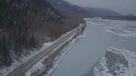 4K aerial stock footage following Old Glenn Highway next to an icy river and snow, Butte, Alaska Aerial Stock Footage | AK0001_1278