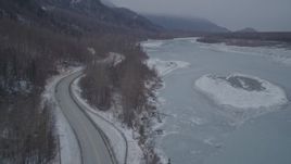 4K aerial stock footage flying between Old Glenn Highway and icy river over snow, Butte, Alaska Aerial Stock Footage | AK0001_1279