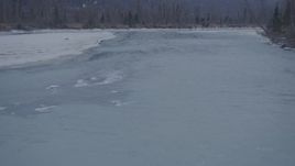 4K aerial stock footage flying over icy river between snow covered shore, Knik River Valley, Alaska Aerial Stock Footage | AK0001_1297