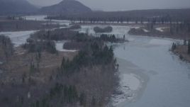 4K aerial stock footage flying over snow covered forest and icy river, Knik River Valley, Alaska Aerial Stock Footage | AK0001_1299