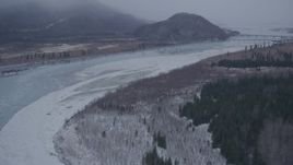 4K aerial stock footage flying over icy river toward Glenn Highway bridge, Knik River Valley, Alaska in snow Aerial Stock Footage | AK0001_1300