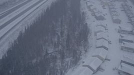 4K aerial stock footage flying over apartment buildings along Glenn Highway, falling snow, Eagle River, Alaska Aerial Stock Footage | AK0001_1314