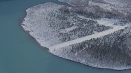 4K aerial stock footage orbiting snow covered, wooded shore of Eklutna Lake, Alaska Aerial Stock Footage | AK0001_1356