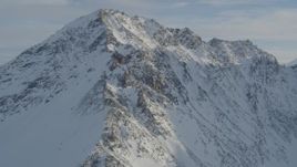Approach and fly over a rocky, snow covered mountain peak, Chugach Mountains, Alaska Aerial Stock Footage | AK0001_1374