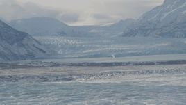 4K aerial stock footage snow covered glacier spilling into Inner Lake George, from Knik Glacier, Alaska Aerial Stock Footage | AK0001_1428
