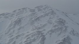 4K aerial stock footage flying up and over a snow covered mountain slope, Chugach Mountains, Alaska Aerial Stock Footage | AK0001_1499