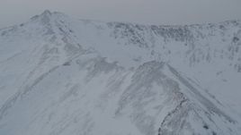 4K aerial stock footage flying up a snowy mountain slope to reveal a valley, Chugach Mountains, Alaska Aerial Stock Footage | AK0001_1502