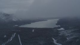 4K aerial stock footage descending through clouds revealing Eklutna Lake, Alaska in snow Aerial Stock Footage | AK0001_1554