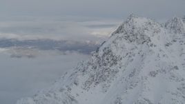 4K aerial stock footage low clouds covering Butte, snowy mountain peak, Chugach Mountains, Alaska Aerial Stock Footage | AK0001_1564