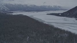 4K aerial stock footage flying toward snow covered wooded bank of Knik River, Alaska Aerial Stock Footage | AK0001_1576